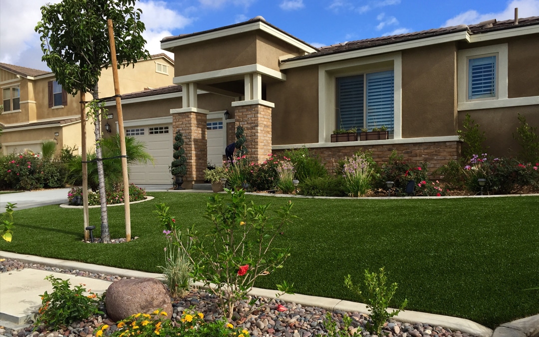 Yard in front of a home and garage made of synthetic grass